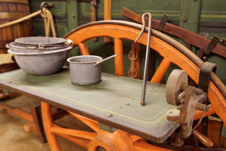 The chuck wagon's shelves hang over the wheels. Notice the blade sharpener on the right.